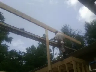Carpenter setting a ridge beam over a new addition frame — Ice Dam Removal by Roofing Brothers in Grayling