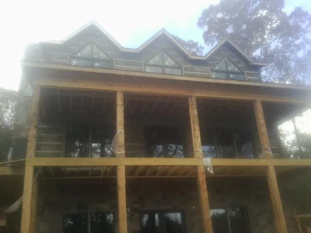 Dormers and porch framing on a large log home under construction — Roof Coating work by our crew in Grayling