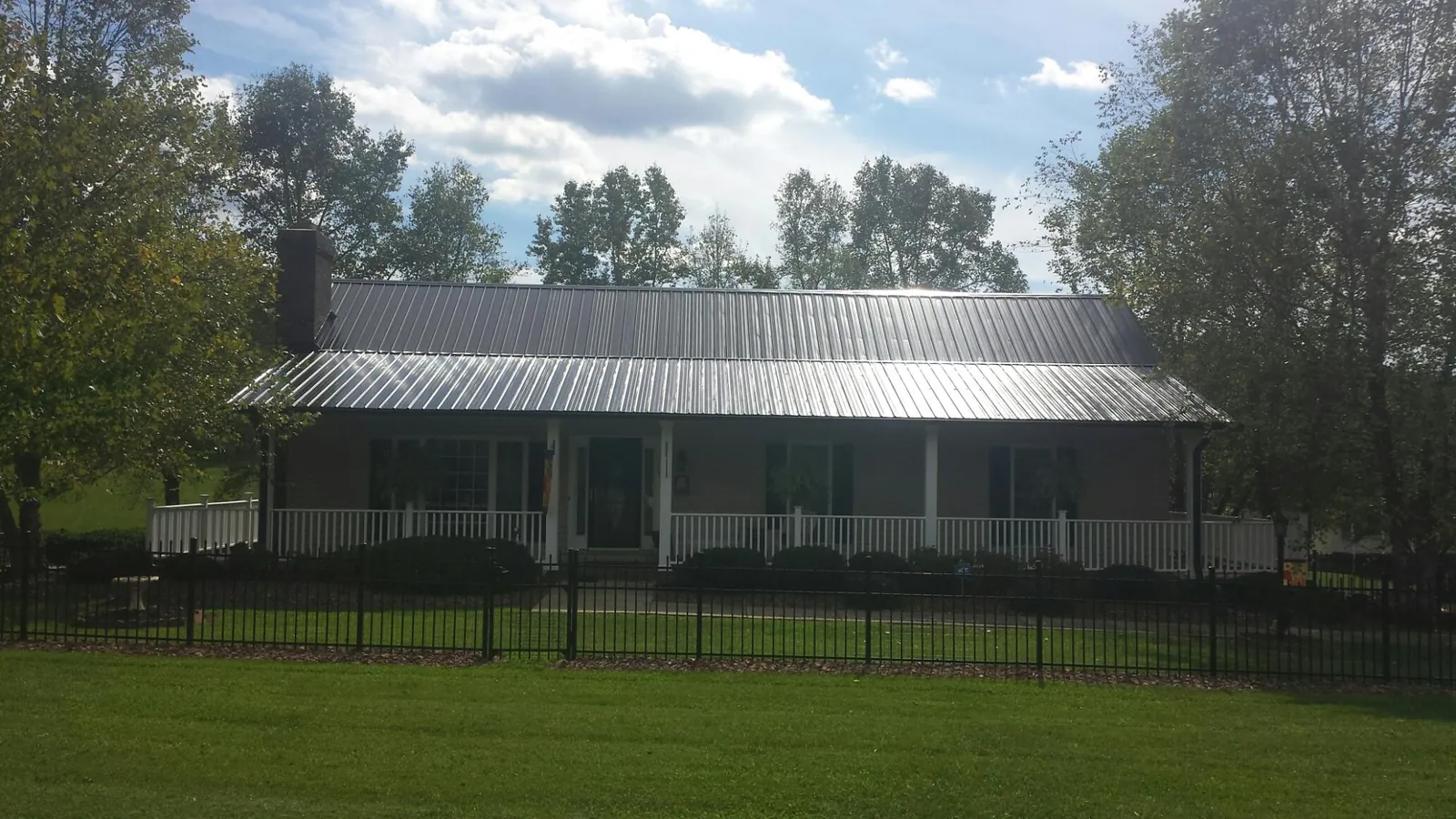 Gray metal roof on a brick ranch with a full width front porch — Gutter Guard Installation work by our crew in Grayling