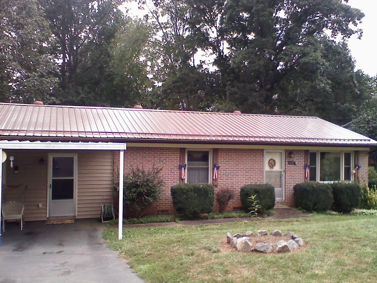 Bronze metal roof and carport on a brick ranch home — Roof Repair work by our crew in Grayling